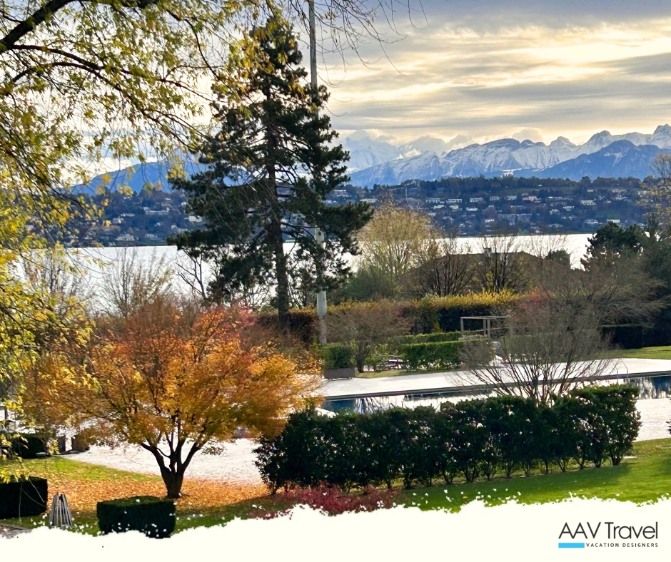 Scenic view of Lake Geneva framed by autumn trees, featuring mountains in the background and a tranquil outdoor pool in the foreground.