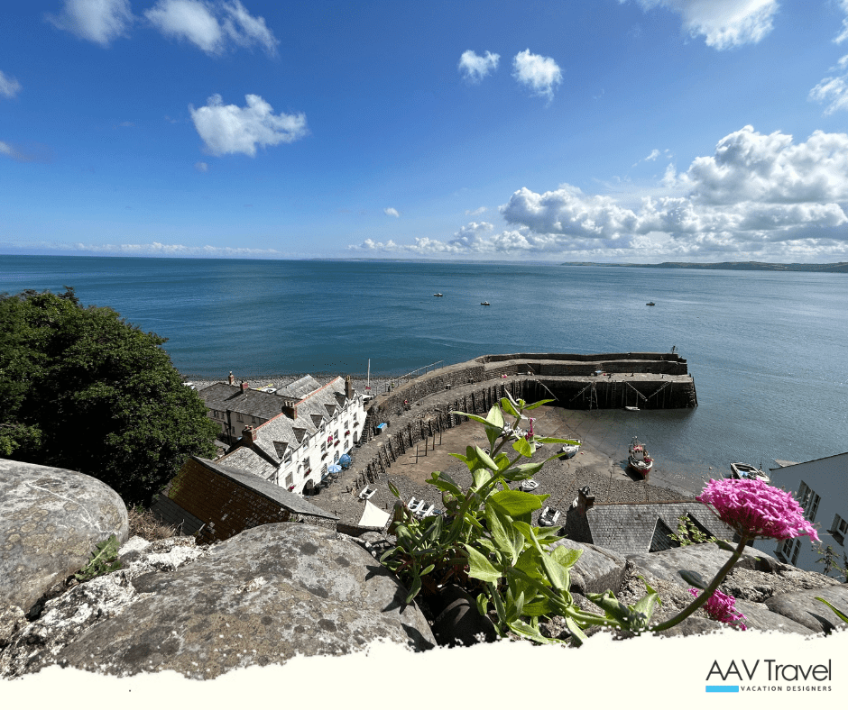 Clovelly harbor bathed in sunshine, with boats moored and stone cottages lining the quay
