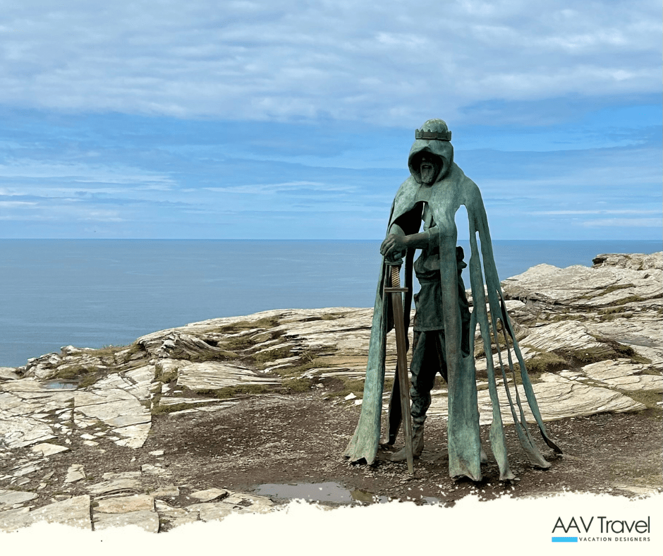 Bronze statue of King Arthur standing on a windswept cliff at Tintagel Castle