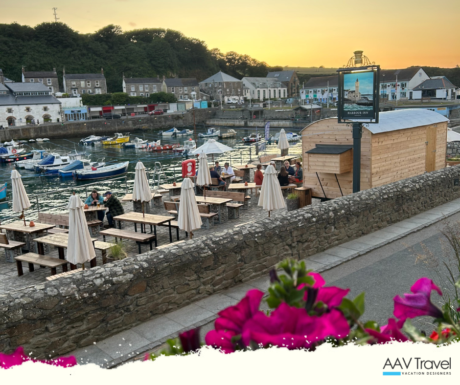 Porthleven Harbour glowing at sunset, with golden light reflecting on calm waters and boats