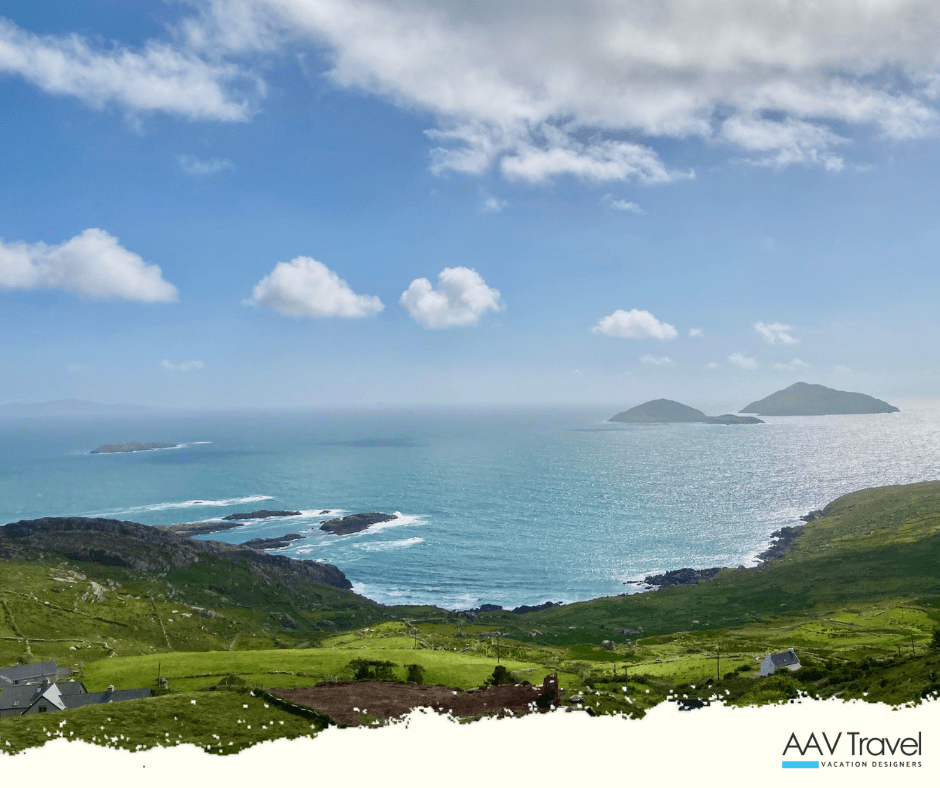 A sweeping view of the Ring of Kerry, with Skellig Michael and Little Skellig rising from the sea in the distance under a soft sky.